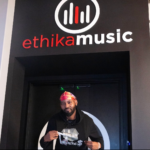 Flyboi Rich wearing a black hoodie and colorful head covering.