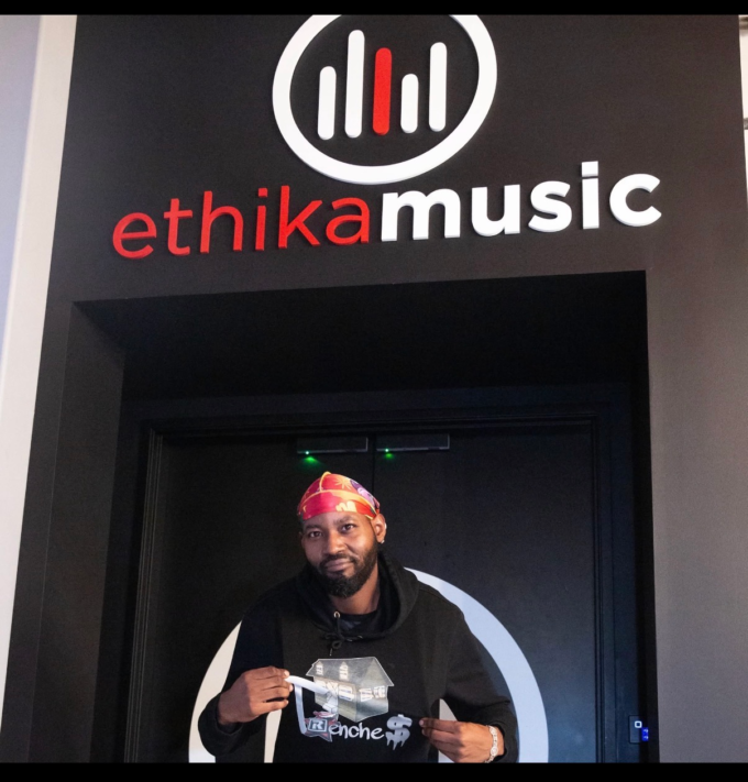 Flyboi Rich wearing a black hoodie and colorful head covering.